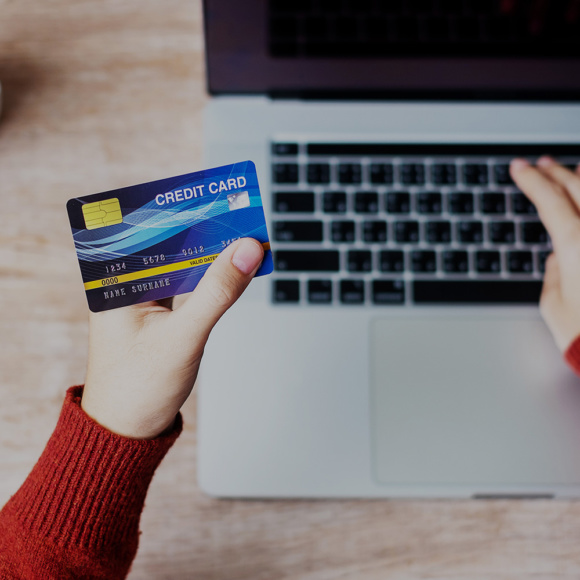Payment Card Data Security | A person holds a credit card above a silver laptop