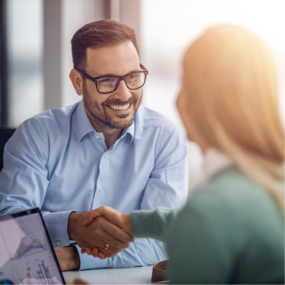 Image of two business people shaking hands while sitting at the working place